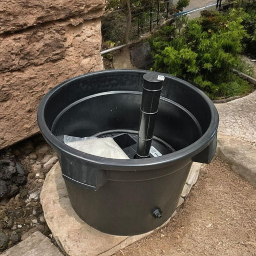 Black plastic container with a handle on a stone surface outdoors